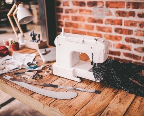 Desk of fashion designer with sewing machine and tools